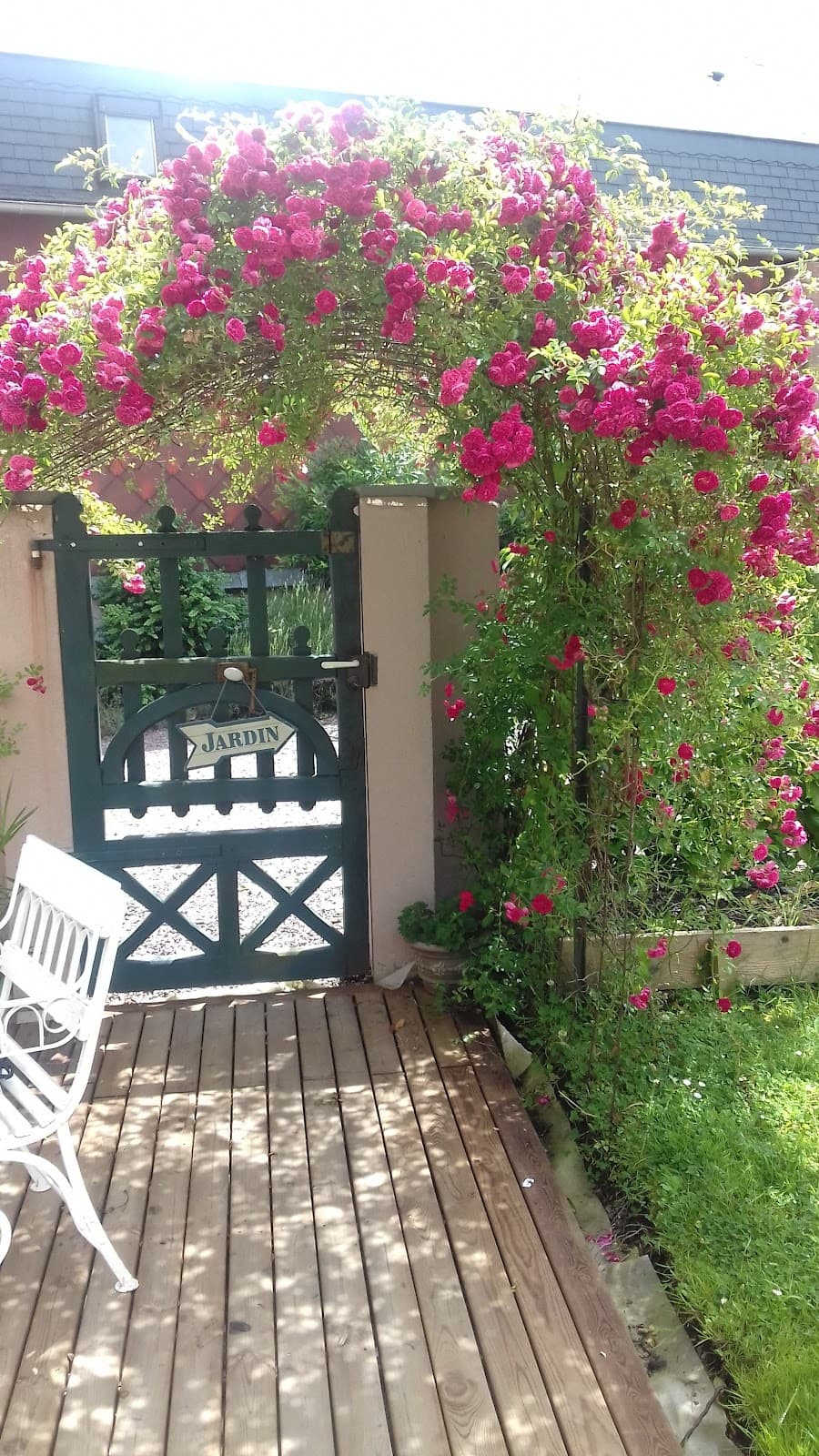 La façade de la maison sous la pergola couverte d’une grimpante en fleurs