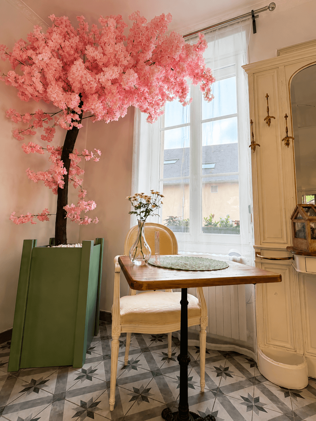 Table près de la fenêtre et arbre fleuri rose posé dans la pièce