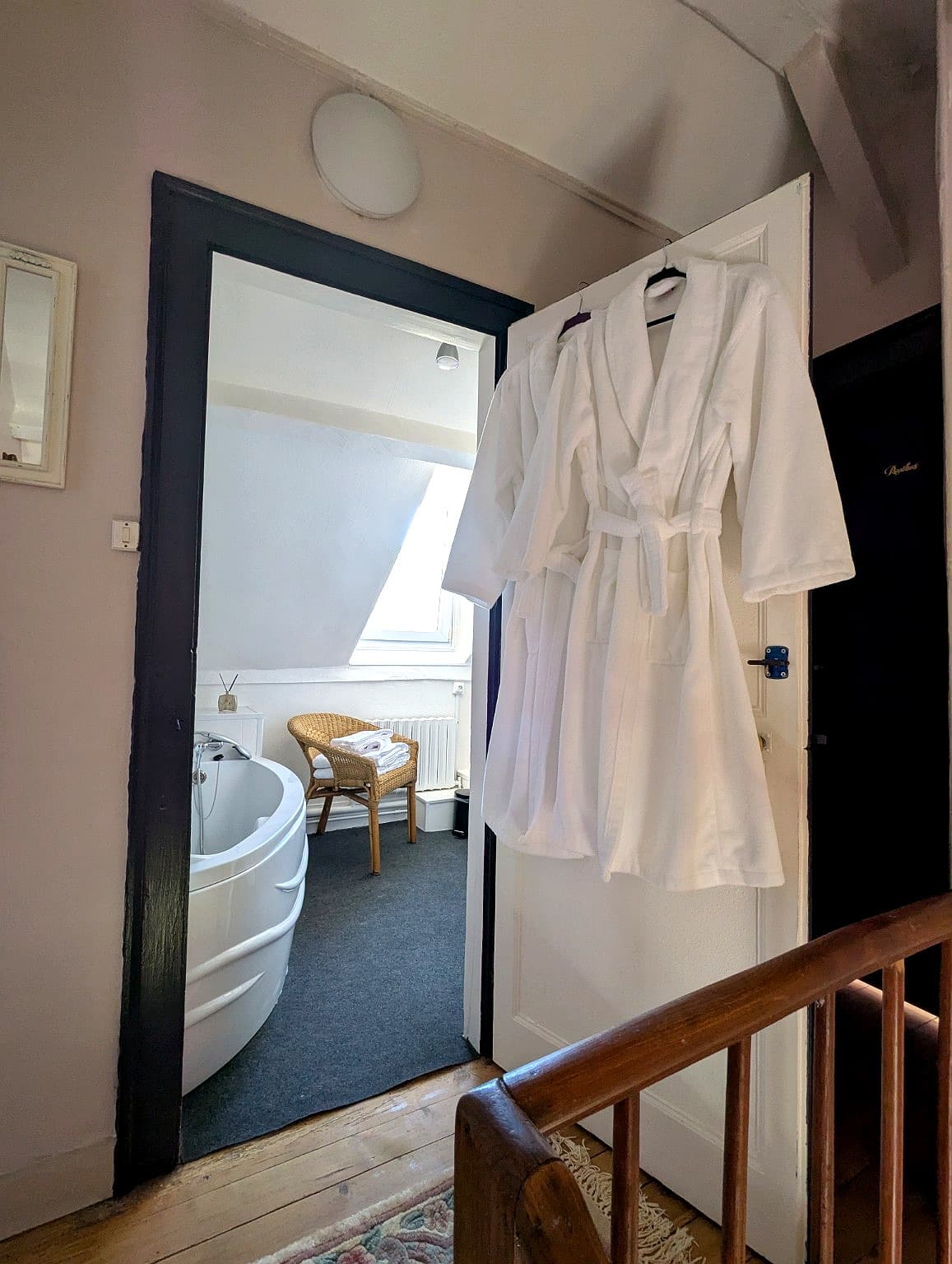 Salle de bain avec baignoire ronde bleue et peignoirs blancs