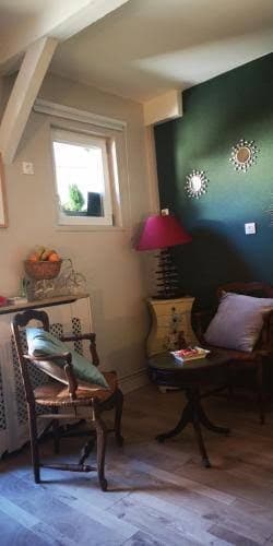 Petit salon privatif, mur vert, table, chaise et coussins colorés