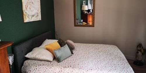 Chambre au mur vert accent, literie claire et coussin orange