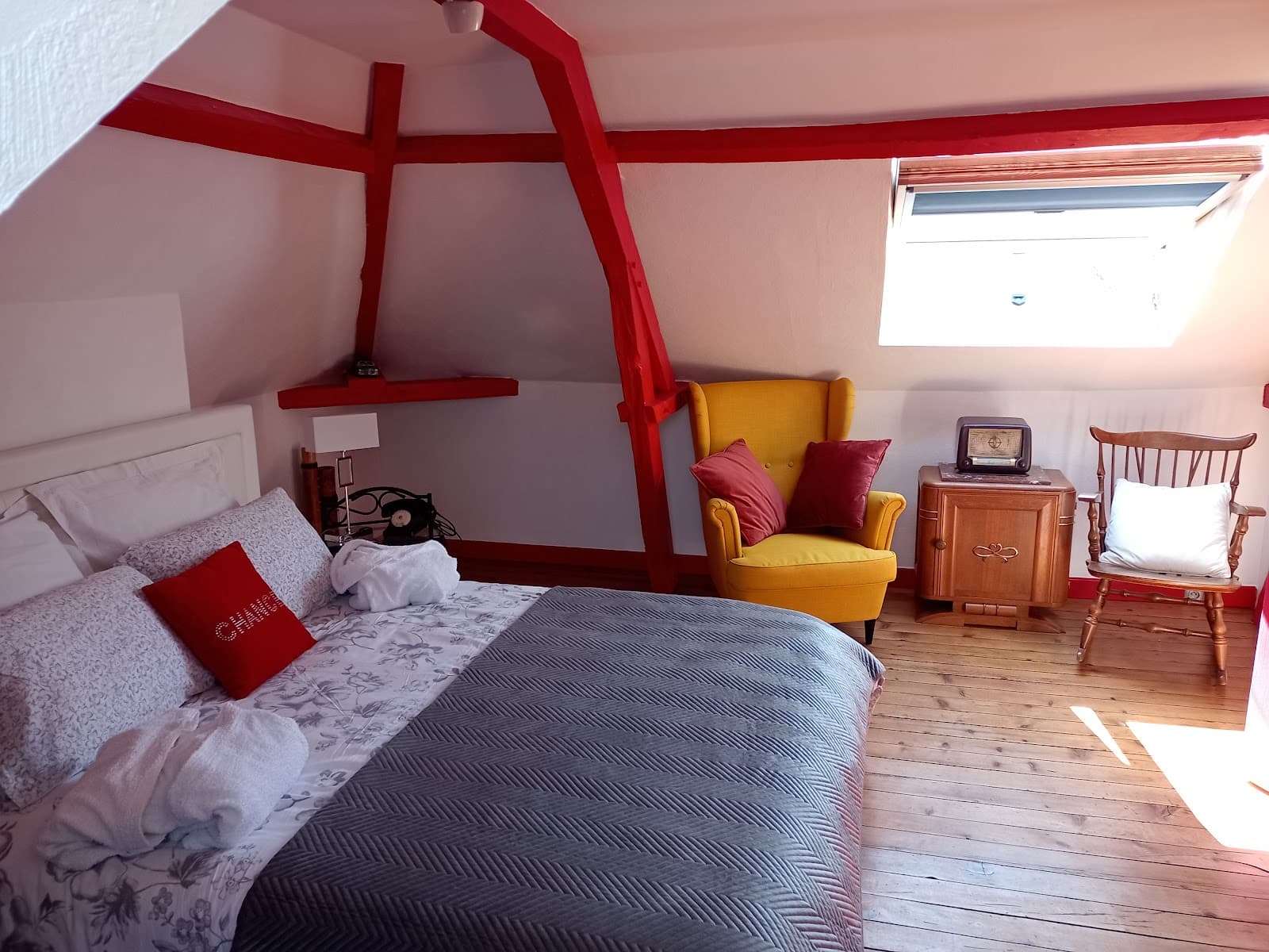 Suite mansardée avec fauteuil jaune, mobilier de bois et claustras