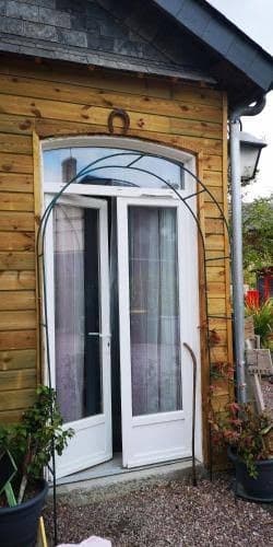 Dépendance de bois aux doubles portes blanches, sous une arche de plantes grimpantes
