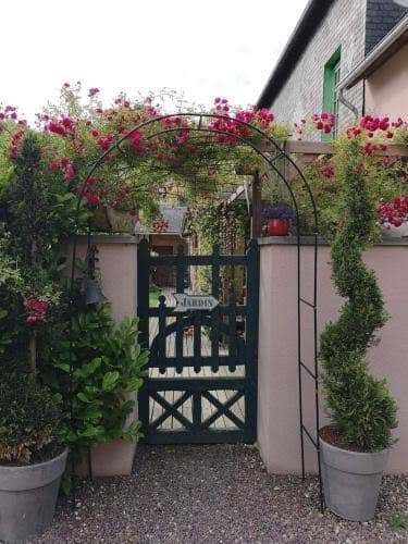 Portail noir du jardin sous une arche de fleurs magenta