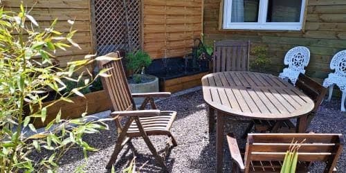 Table ovale de bois et chaises sous les feuillages du jardin